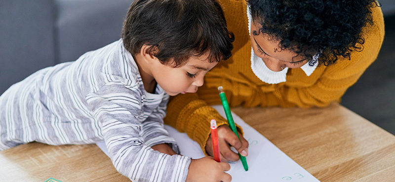 Una mamá y su hijo pequeño coloreando juntos en la casa 