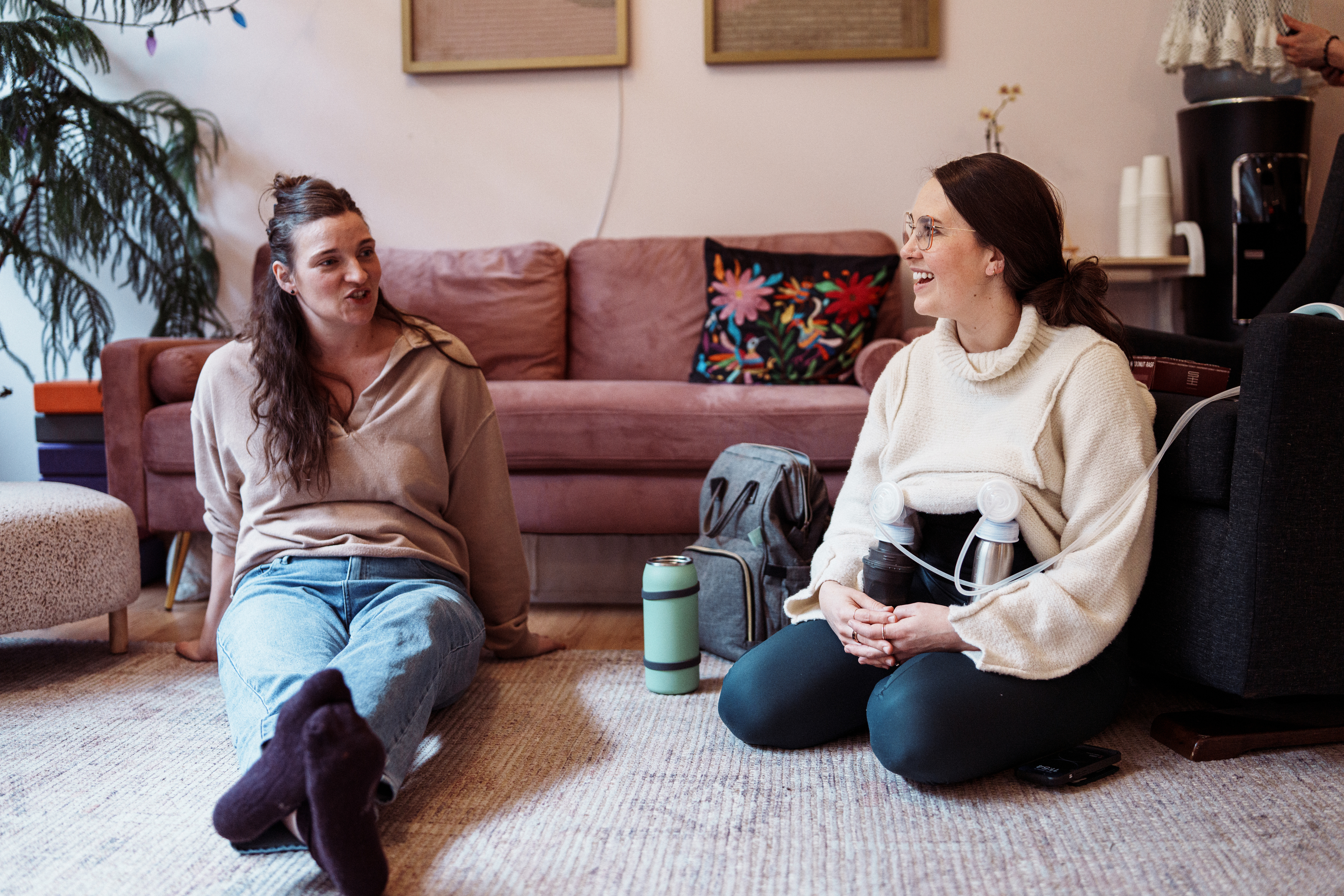 A woman talking to her friend while using a breast pump
