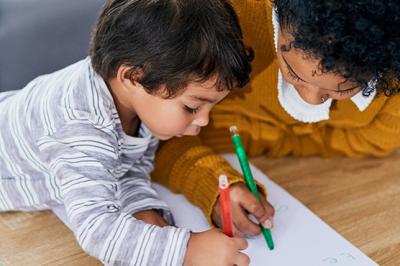 A mother and her young son coloring together at home. 